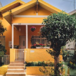 Bright yellow house with lush garden, vibrant flowers, and welcoming porch entrance.